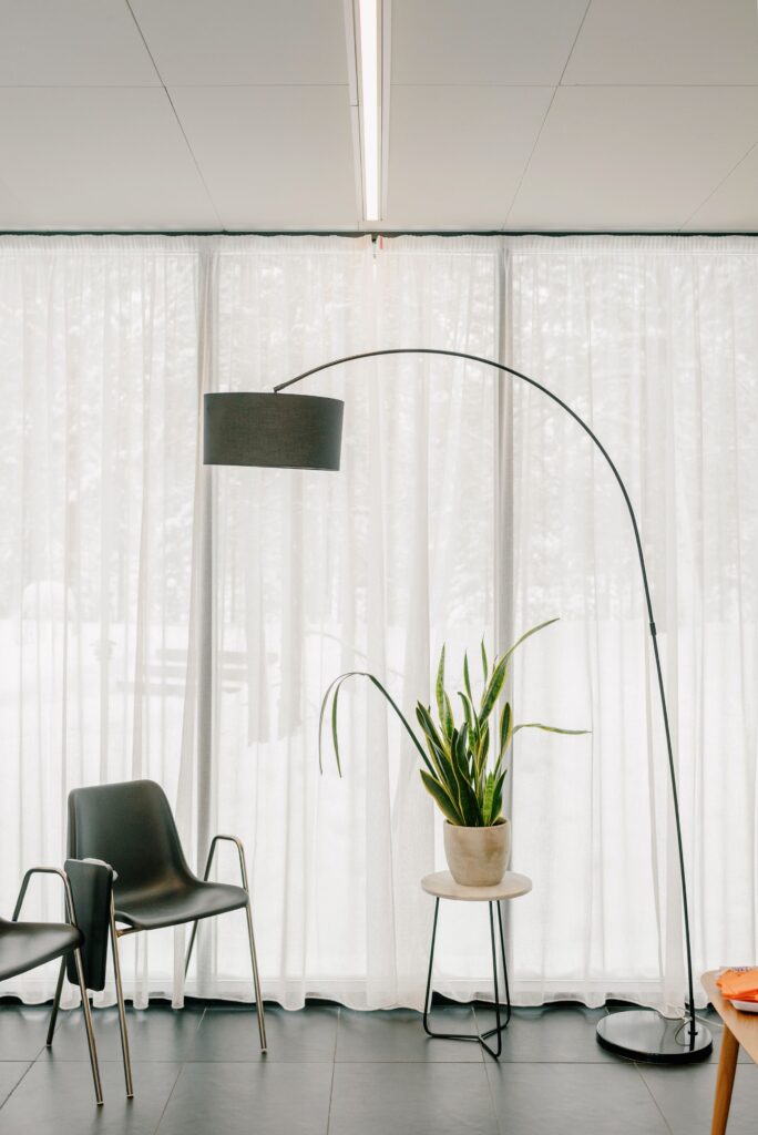 Stylish office interior with a decorative plant, empty seats, and a tall lamp.